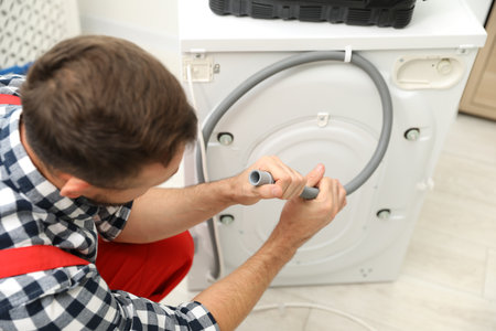 Professional repairman fixing broken washing machine indoorsの写真素材