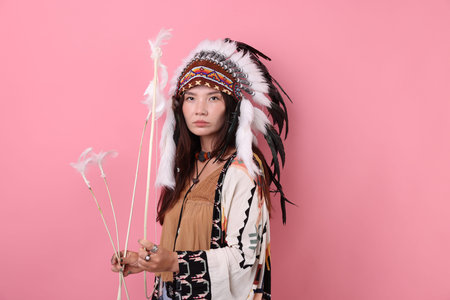 Shaman woman in native headdress with bow and arrows on pink backgroundの写真素材