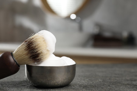 Shaving brush and foam on gray textured table indoors, closeup with space for text. Barber's toolsの写真素材