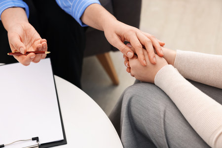 Psychologist supporting woman during therapy session indoors, closeupの写真素材