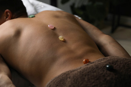 Man undergoing crystal therapy to heal or restore his aura indoors, closeupの写真素材