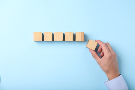 Man with wooden cubes on light blue background, top viewの写真素材