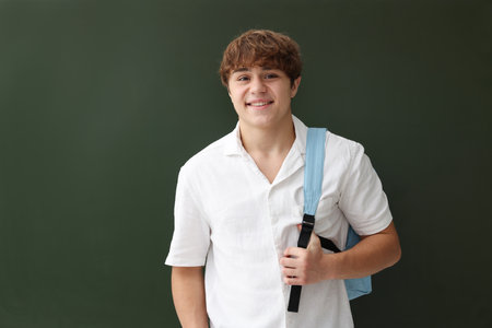Back to school. Student with backpack near chalkboard indoorsの写真素材