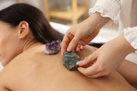 Woman undergoing crystal therapy to heal or restore her aura indoors, closeupの写真素材