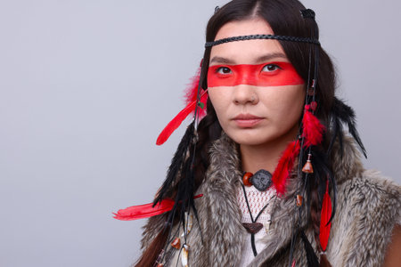 Shaman woman with face painting on light gray background, space for text