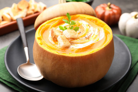 Tasty pumpkin cream soup with croutons and parsley served in pumpkin on table, closeupの写真素材