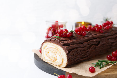 Delicious Yule log (traditional Christmas cake) with redcurrant on white table, closeup. Space for textの写真素材