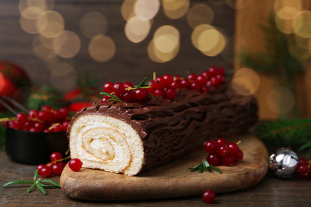 Delicious Yule log (traditional Christmas cake) with redcurrant on wooden table, closeupの写真素材