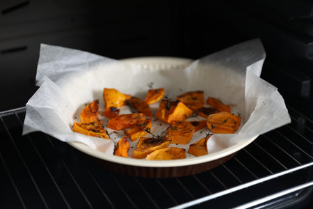 Baking dish with pieces of pumpkin and thyme in oven, closeupの写真素材