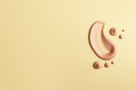 Samples of foundation on beige background, flat lay. Space for textの写真素材