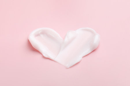 Heart shape made of moisturizing cream on pink background, closeupの写真素材