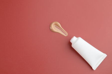 Tube with foundation on red background, top view. Space for textの写真素材