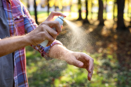 Man spraying tick repellent onto arm in park, closeup. Space for textの写真素材