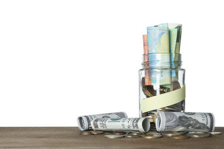 Jar with blank note and money on wooden table against white background