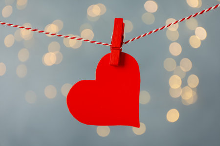 Paper heart hanging on string against gray background, bokeh effectの写真素材