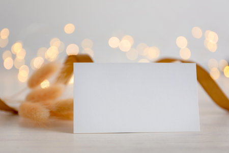 Blank card and decor on white wooden table against blurred background, bokeh effect. Mockup for designの写真素材