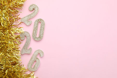 New 2026 Year. Golden numbers and shiny tinsel on pink background, flat lay. Space for text
