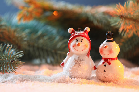 Cute decorative snowmen on artificial snow against blurred background, closeup. Space for textの写真素材