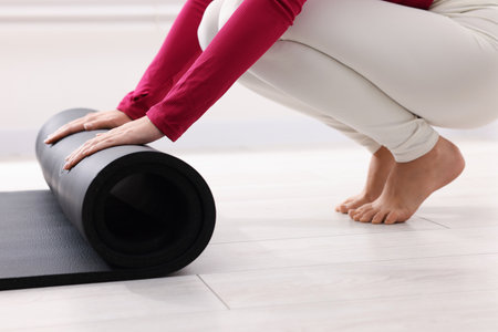 Woman unrolling mat in yoga studio, closeupの写真素材