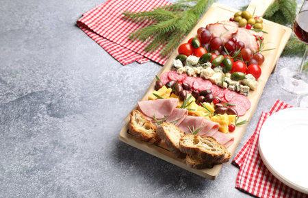 Christmas Charcuterie board with snacks and fir branches on gray textured table, closeup. Space for textの写真素材