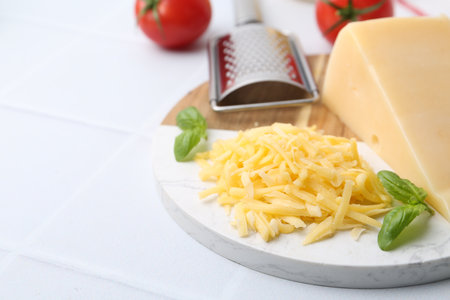 Grater, basil, grated and piece of cheese on white table, closeup. Space for textの写真素材