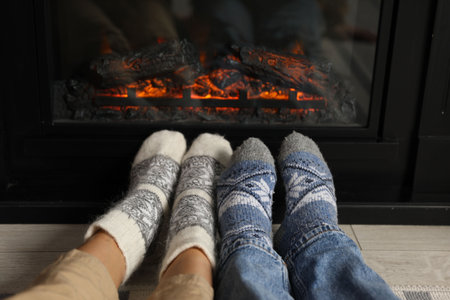 Couple in warm socks resting near fireplace at home, closeupの写真素材