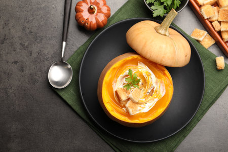 Tasty pumpkin cream soup with croutons and parsley served in pumpkin on gray table, flat lay. Space for textの写真素材