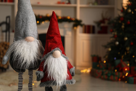 Funny Christmas gnomes in festive decorated room, space for text