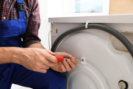 Professional repairman fixing broken washing machine indoors, closeupの写真素材