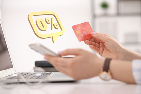 Woman with credit card using smartphone at table, closeup. Speech bubble with 0 percent sign above device. Zero commissionの写真素材