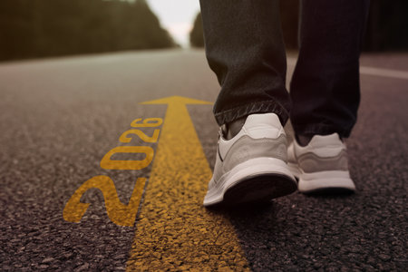 New 2026 Year. Man walking along arrow with numbers on asphalt, closeupの写真素材