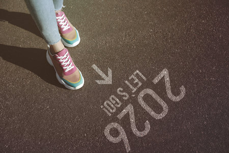 New 2026 Year. Woman walking on asphalt with arrow, phrase Let's Go! and numbers, closeupの写真素材