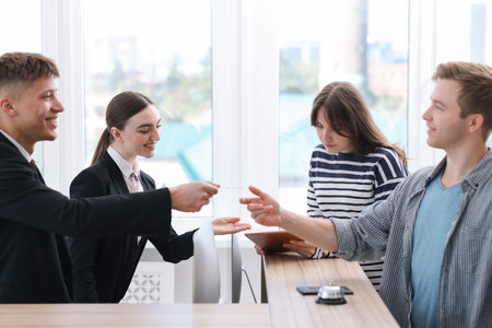 Receptionist and hostess working with guests at reception desk in hotelの写真素材