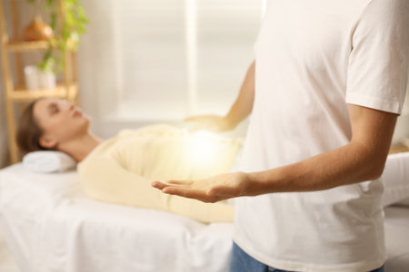 Reiki master showing his hand while healing patient's aura during therapy indoors, closeupの写真素材
