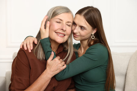 Mother and daughter hugging on sofa at home