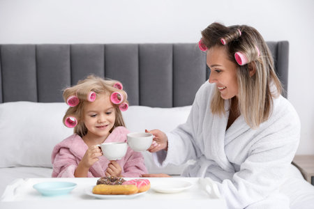 Mother and daughter having tea party on bed at homeの写真素材