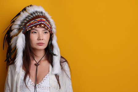 Shaman woman in native American Indian headdress on orange background, space for text