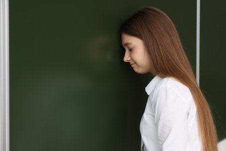 Back to school. Sad student at chalkboard indoors, space for textの写真素材