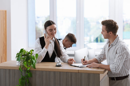 Receptionist working with guest at reception desk in hotelの写真素材