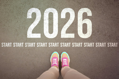 New Year. Woman standing in front of line of words Start and numbers 2026 on asphalt, top viewの写真素材