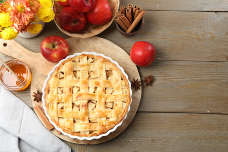 Delicious homemade pie, fresh apples, honey and flowers on wooden table, flat lay. Space for textの写真素材