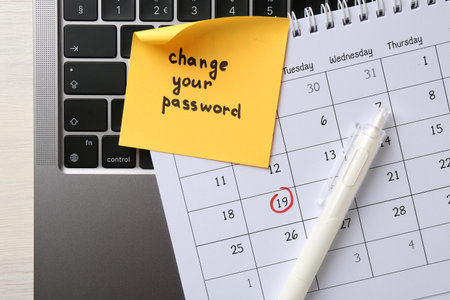 Note with phrase Change your password, pen, calendar and laptop on white wooden desk, closeupの写真素材