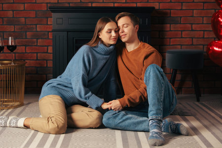 Lovely couple on floor near fireplace in roomの写真素材