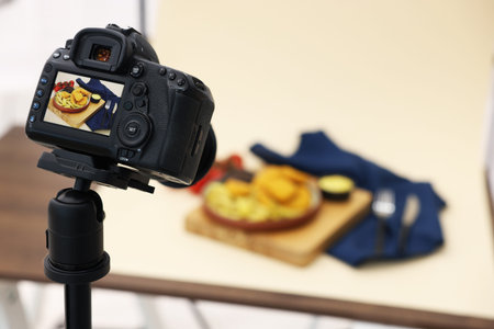 Shooting chicken nuggets, French fries, sauces and tomatoes with camera in studio, selective focus....