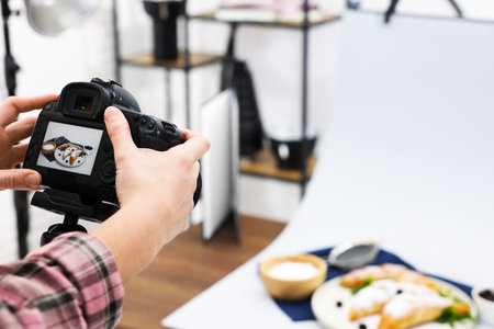 Woman shooting tasty croissants and ingredients with camera in studio, selective focus. Professional...