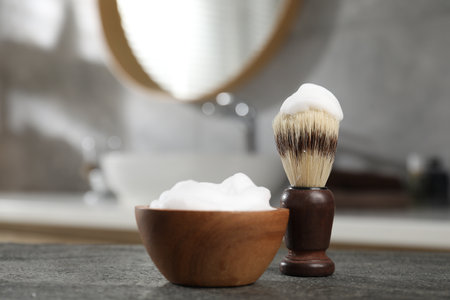 Shaving brush and foam on gray textured table indoors, closeup with space for text. Barber's toolsの写真素材