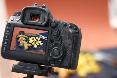 Shooting chicken wings, potato wedges and spices with camera in studio, selective focus....