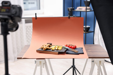 Shooting chicken wings, potato wedges, spices and tomatoes with camera in studio. Professional food photographyの写真素材