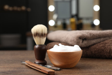 Shaving brush, foam, straight razor and towels on wooden table in barbershop, closeupの写真素材