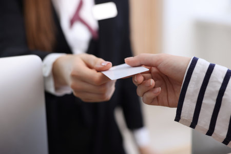 Receptionist giving hotel key card to guest at reception indoors, closeupの写真素材